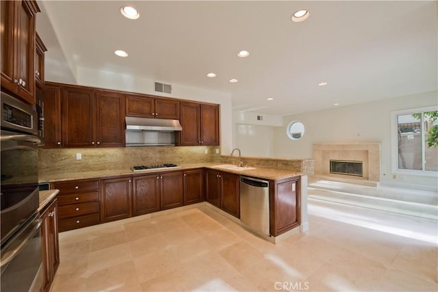 kitchen featuring sink, a fireplace, light stone countertops, and appliances with stainless steel finishes