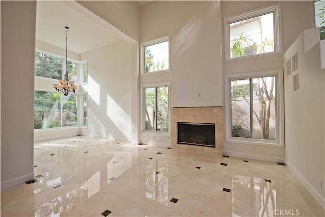 unfurnished living room featuring a high ceiling, a tile fireplace, and a healthy amount of sunlight