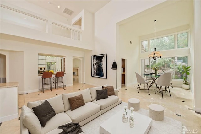 living room with a towering ceiling, a wealth of natural light, and a chandelier