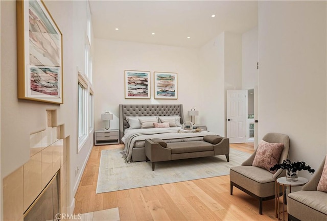 bedroom with a towering ceiling and light wood-type flooring