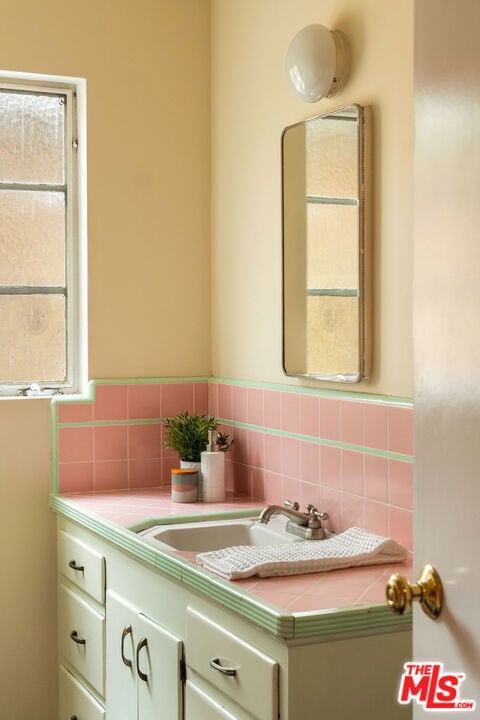 bathroom featuring a healthy amount of sunlight, vanity, and decorative backsplash