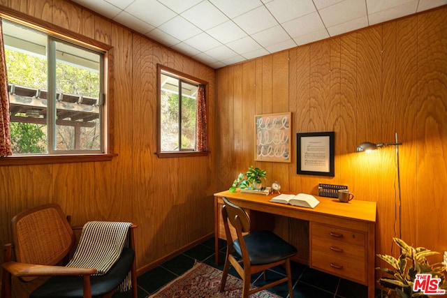 home office featuring dark tile patterned flooring and wooden walls