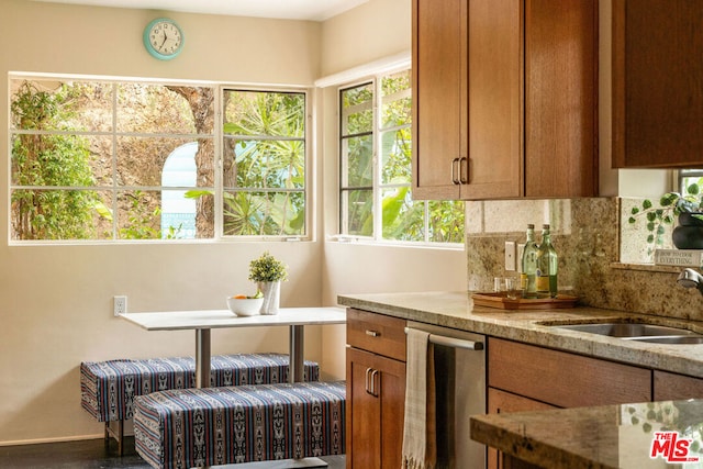 kitchen with radiator, dishwasher, sink, decorative backsplash, and light stone countertops