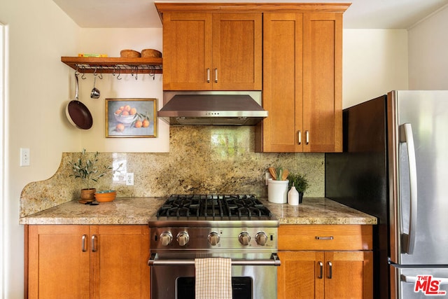 kitchen featuring stainless steel appliances, backsplash, light stone counters, and wall chimney exhaust hood