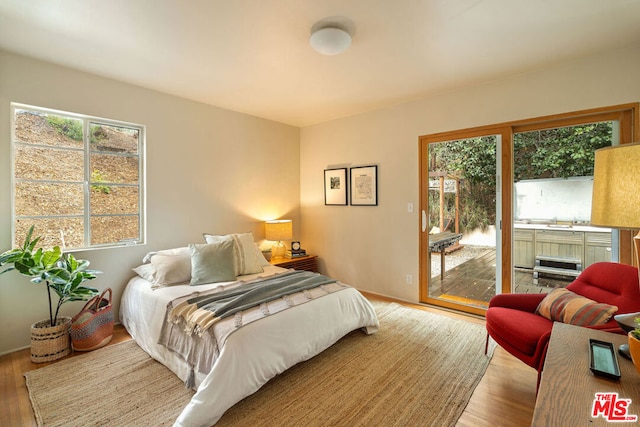 bedroom featuring multiple windows, access to outside, and light hardwood / wood-style floors