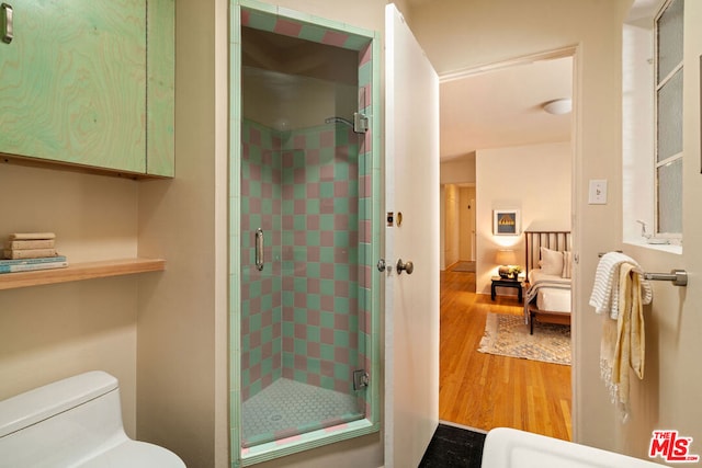 bathroom featuring wood-type flooring, toilet, and a shower with door