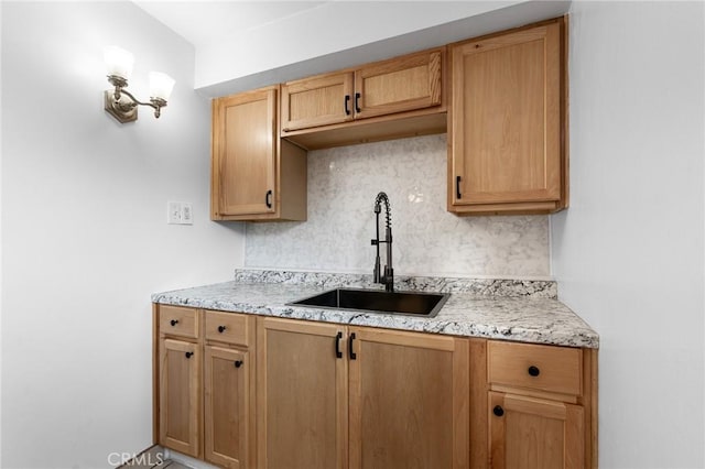 kitchen featuring light stone countertops, sink, and decorative backsplash