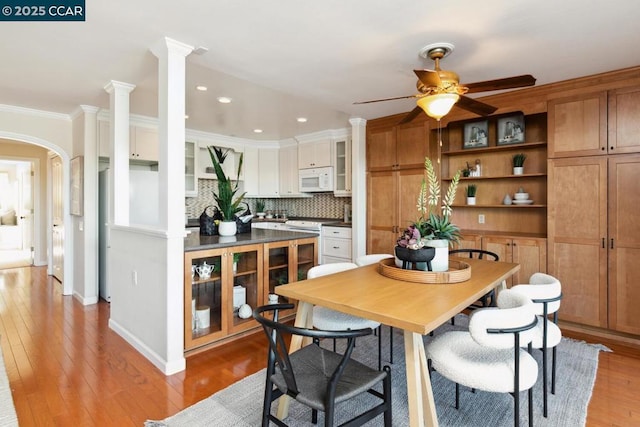 dining space with light hardwood / wood-style flooring, ornamental molding, decorative columns, and ceiling fan