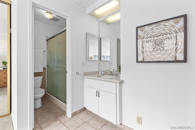 bathroom featuring tile patterned flooring, vanity, an enclosed shower, and toilet