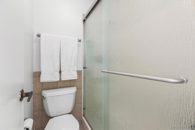 bathroom featuring a shower with shower door and toilet