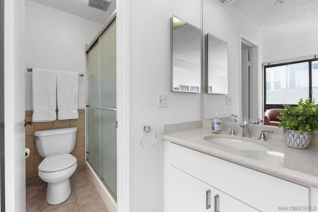 bathroom featuring tile patterned floors, toilet, a shower with shower door, and vanity