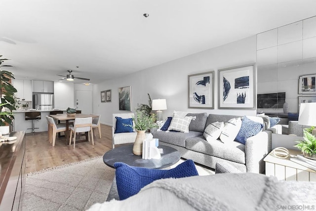 living room featuring sink, ceiling fan, and light hardwood / wood-style flooring