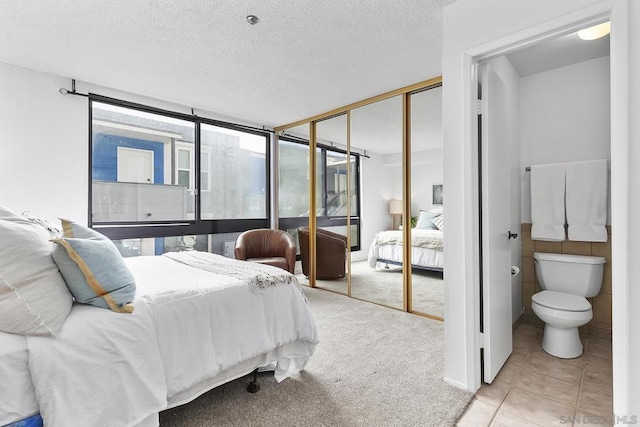 carpeted bedroom featuring a closet, a wall of windows, and a textured ceiling