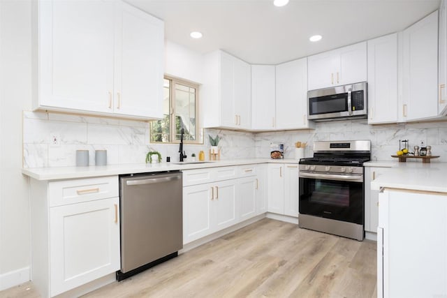 kitchen with sink, white cabinetry, tasteful backsplash, appliances with stainless steel finishes, and light hardwood / wood-style floors