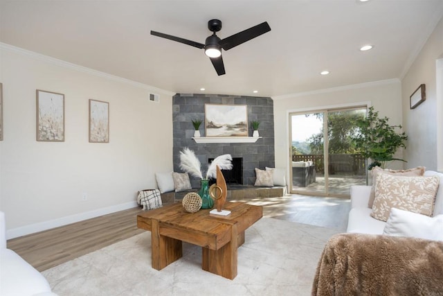 living room featuring crown molding, a large fireplace, ceiling fan, and light wood-type flooring