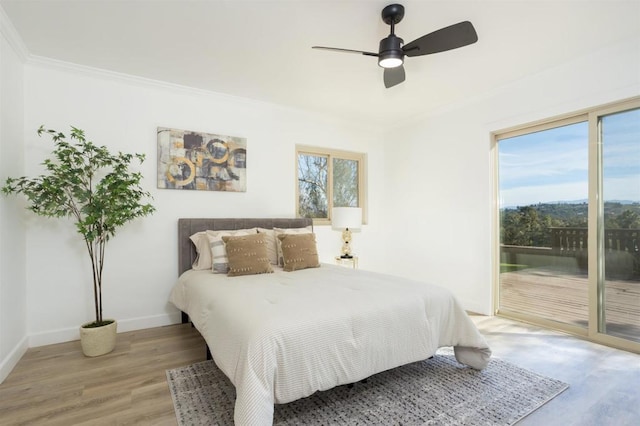 bedroom featuring multiple windows, ornamental molding, hardwood / wood-style flooring, and access to outside