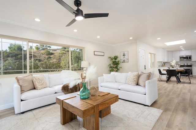 living room with ceiling fan, ornamental molding, and light hardwood / wood-style floors