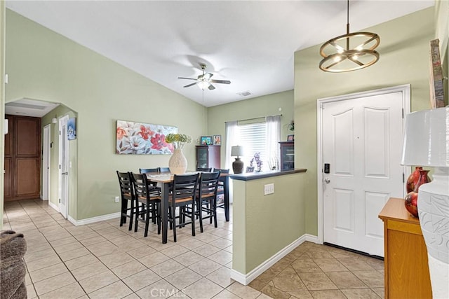 dining room with vaulted ceiling, ceiling fan with notable chandelier, and light tile patterned floors