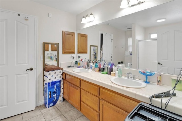 bathroom featuring a shower with door, vanity, and tile patterned floors