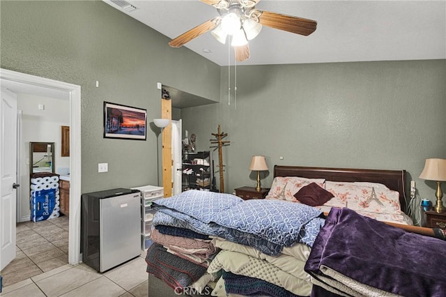 bedroom with light tile patterned floors, vaulted ceiling, stainless steel refrigerator, and ceiling fan