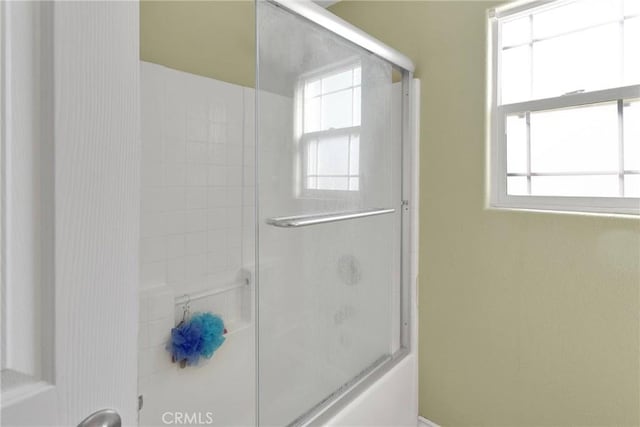 bathroom featuring bath / shower combo with glass door and a wealth of natural light