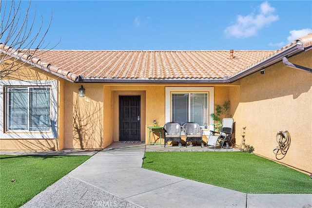 view of exterior entry featuring a lawn and a patio area