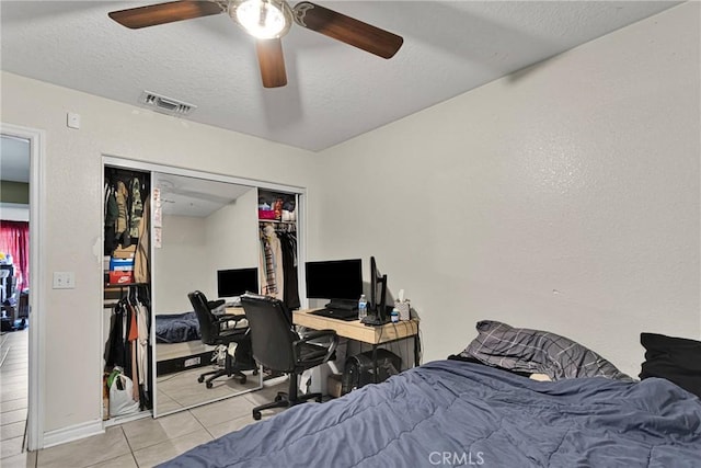 tiled bedroom featuring ceiling fan, a closet, and a textured ceiling