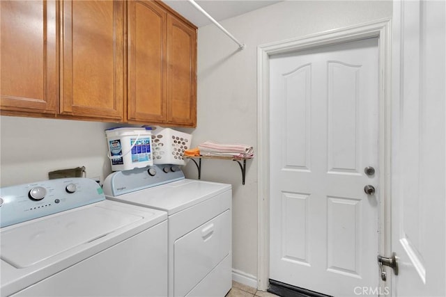 laundry area featuring washing machine and dryer, cabinets, and light tile patterned flooring