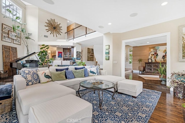 living room featuring ornamental molding, a fireplace, hardwood / wood-style floors, and a high ceiling