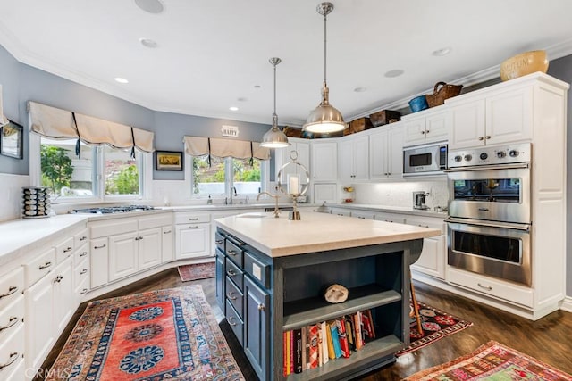 kitchen with decorative light fixtures, white cabinetry, backsplash, stainless steel appliances, and a center island with sink