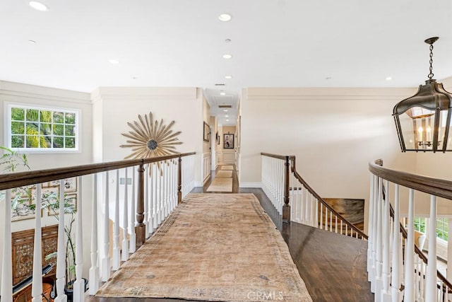 hallway with hardwood / wood-style floors and an inviting chandelier