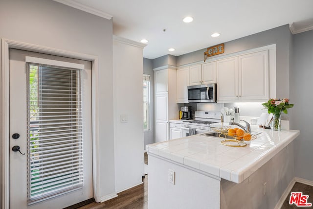 kitchen with dark hardwood / wood-style floors, tile countertops, white gas range, white cabinets, and kitchen peninsula