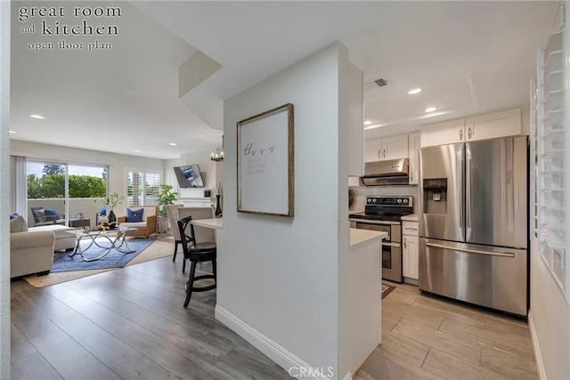 kitchen featuring a breakfast bar area, light hardwood / wood-style floors, white cabinets, and appliances with stainless steel finishes