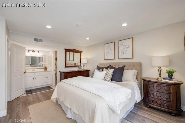 bedroom with ensuite bathroom and light hardwood / wood-style flooring