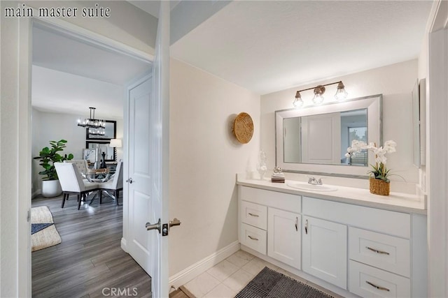 bathroom with vanity, wood-type flooring, and an inviting chandelier