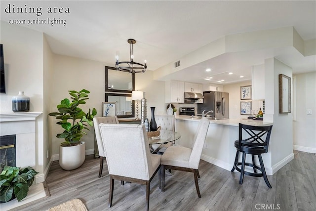 dining area with a high end fireplace, light hardwood / wood-style floors, and a chandelier