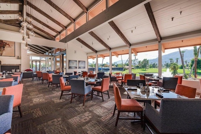 dining room featuring dark carpet, a mountain view, beam ceiling, and a healthy amount of sunlight