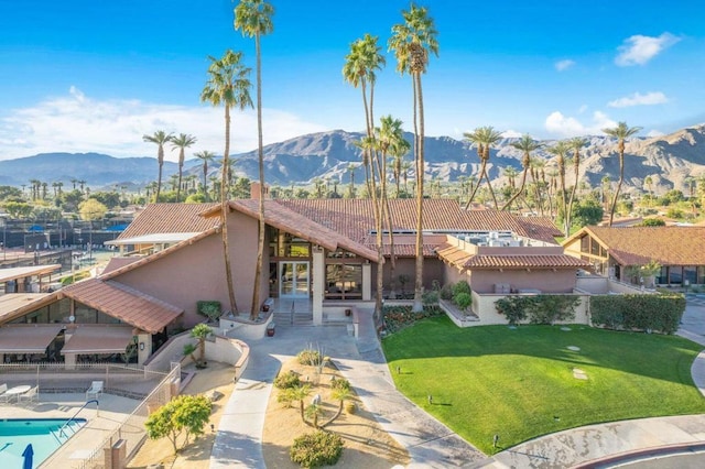 exterior space featuring a fenced in pool, a patio, a mountain view, and a front lawn