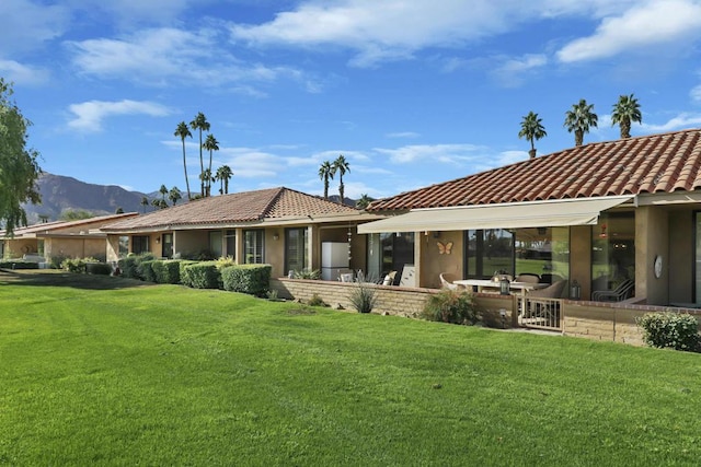 rear view of property featuring a mountain view, a yard, and a patio area