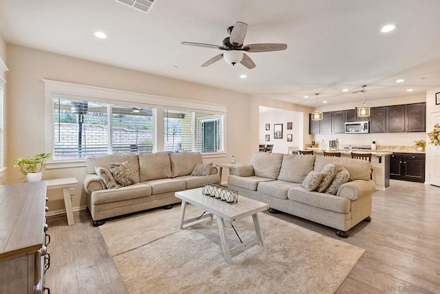 living room with ceiling fan and light wood-type flooring