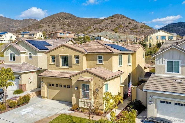 view of front of home with a garage, a mountain view, and solar panels