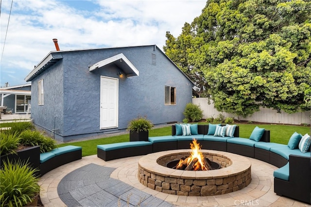 back of property featuring a patio and an outdoor living space with a fire pit