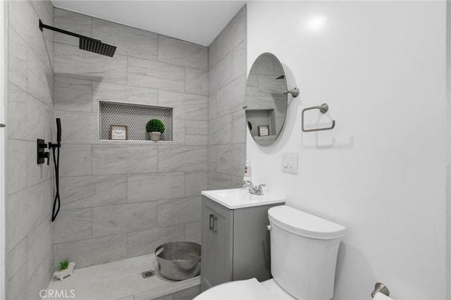 bathroom featuring vanity, toilet, and a tile shower