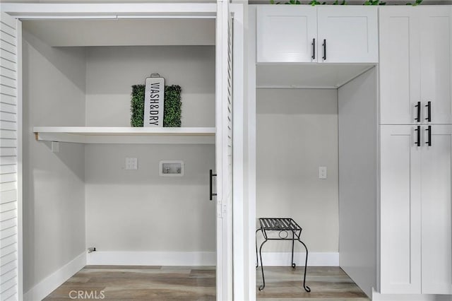 washroom with hookup for a washing machine, light hardwood / wood-style floors, and cabinets