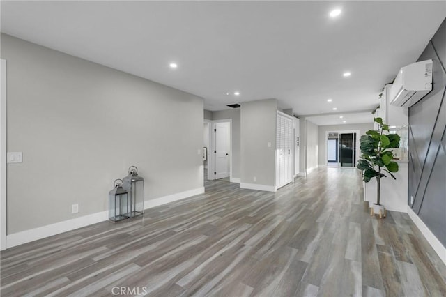 unfurnished living room with a wall mounted AC and light wood-type flooring