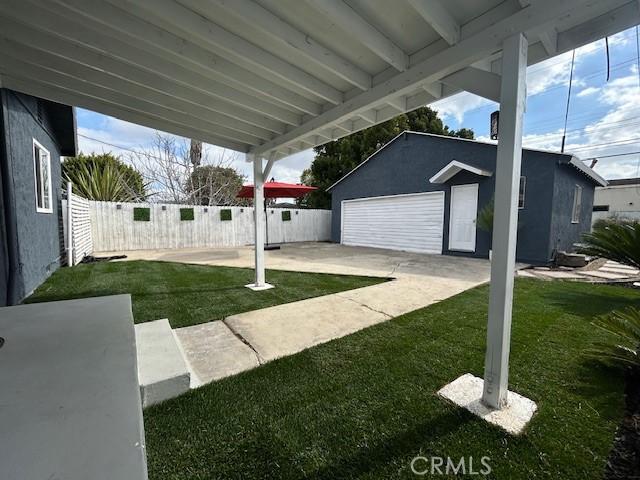 view of yard featuring a garage, an outdoor structure, and a patio