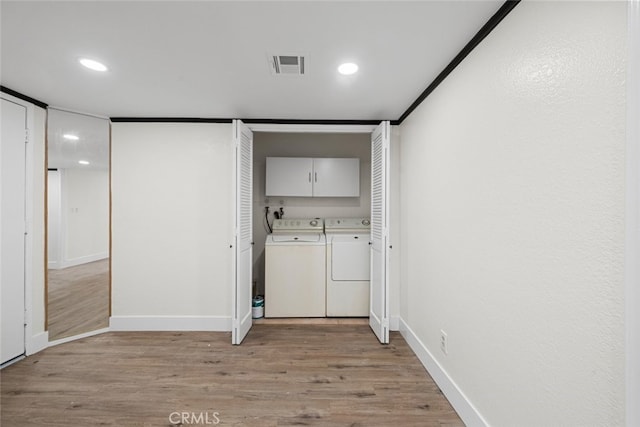 laundry area with separate washer and dryer, cabinets, and light wood-type flooring