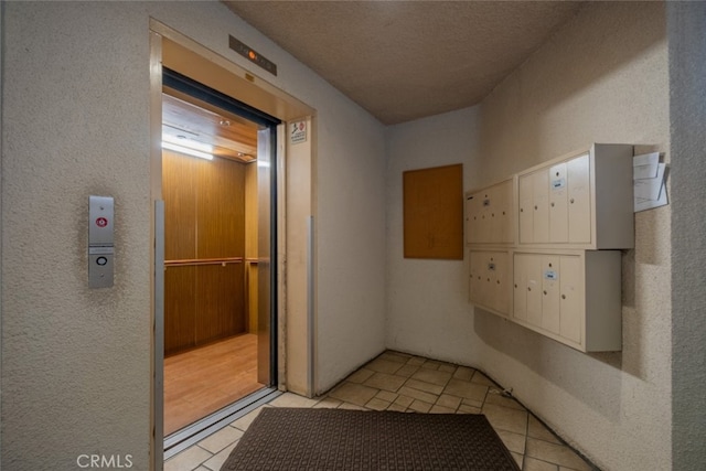 hallway with light tile patterned flooring, a mail area, and elevator