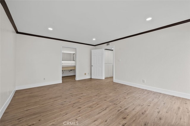 unfurnished bedroom featuring ornamental molding, ensuite bathroom, and light wood-type flooring