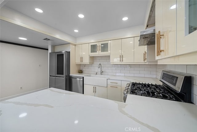 kitchen featuring light stone counters, appliances with stainless steel finishes, sink, and tasteful backsplash